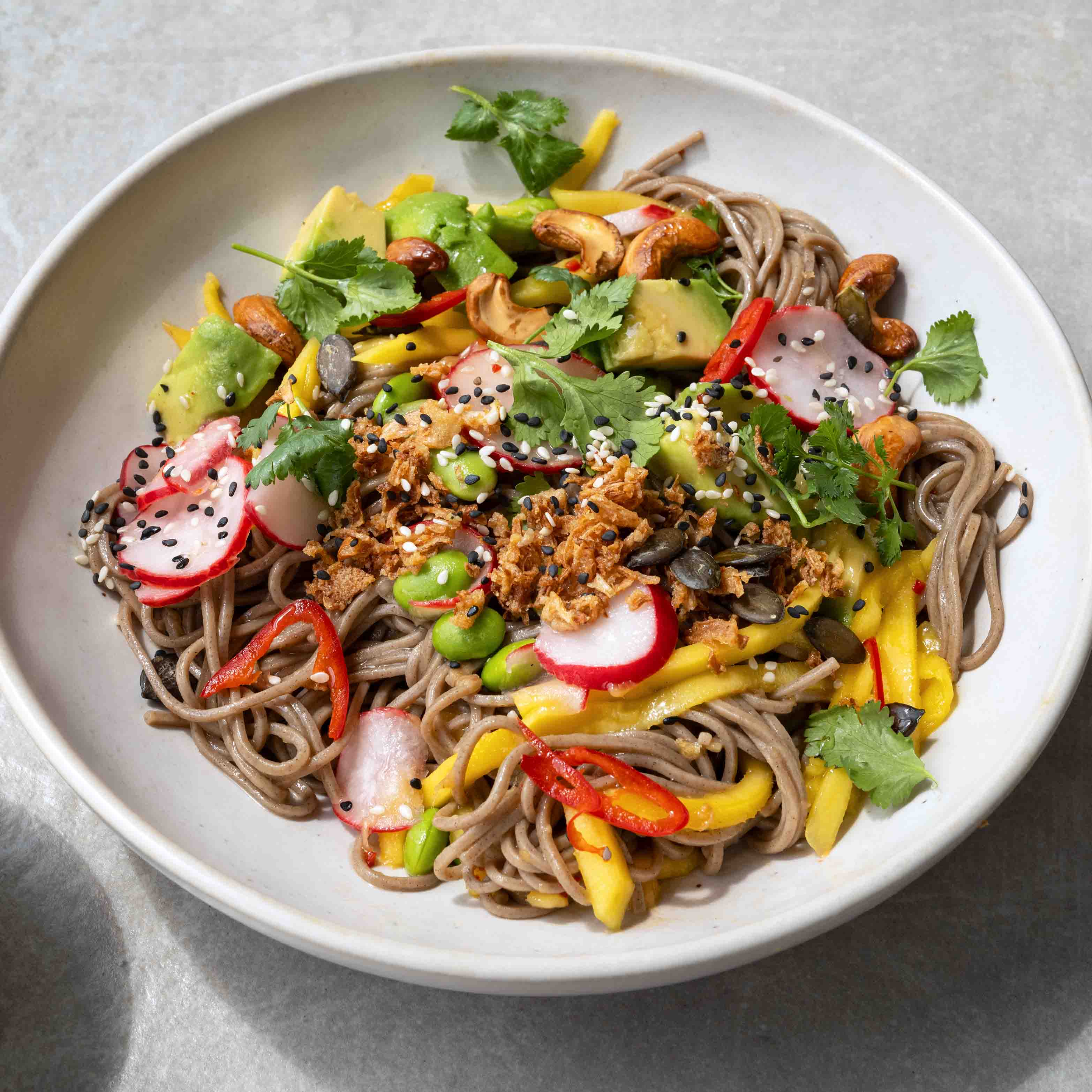 Dish photo for Mango Soba Noodle Salad With Avocado, Edamame, Cashews, Pickled Radish, Toasted Seeds & Crispy Onions