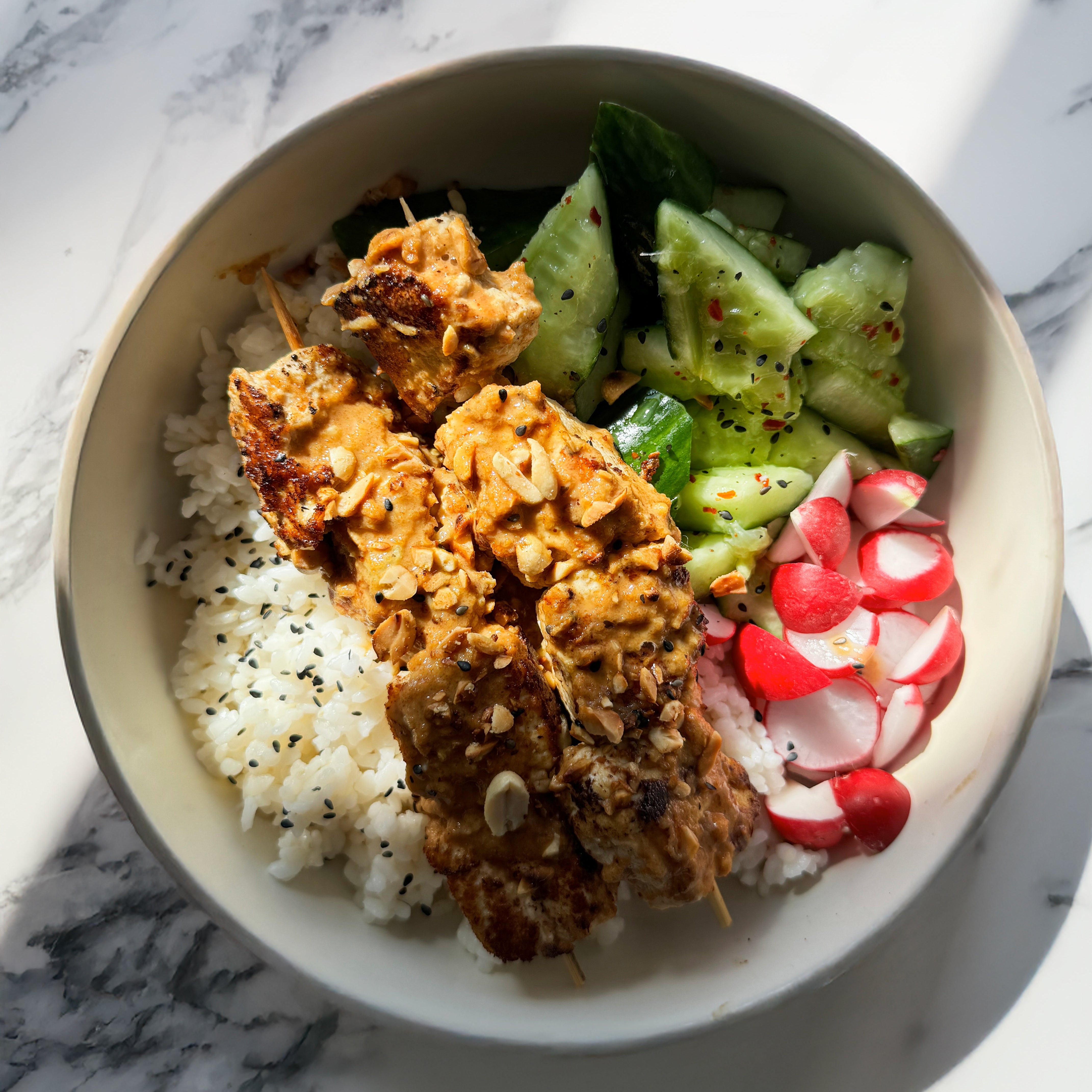 Dish photo for Tofu Satay Skewer Bowl With Zingy Smacked Cucumbers, Pink Radish, Sushi Rice & Sesame Peanut Garnish