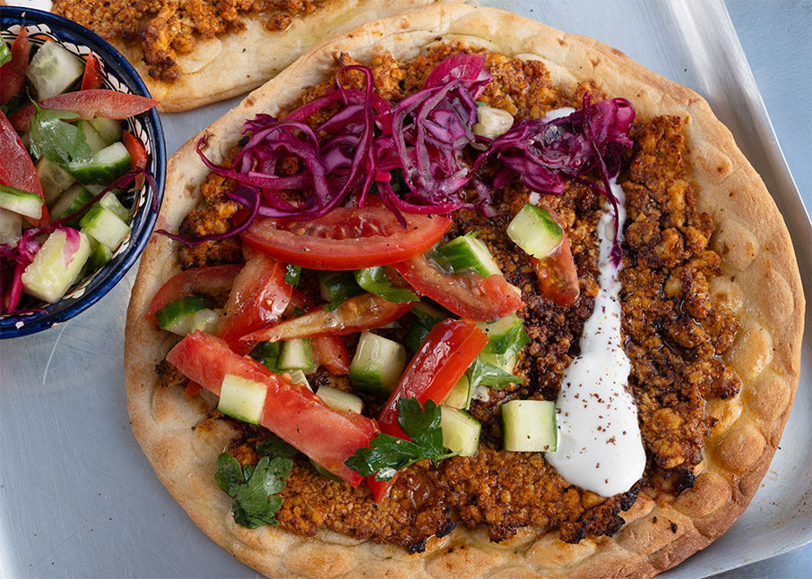 Dish photo for Lahmacun Flatbread With Meaty Spiced Tofu Crumble, Tomato, Cucumber, Sumac Pickled Onion & Garlic Yoghurt
